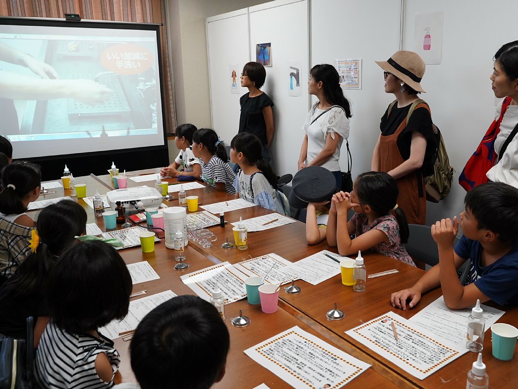 ハンドソープ作りの説明を受けるこどもたち