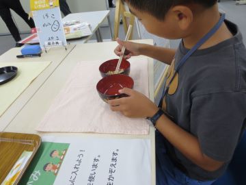 真剣に箸で豆をつかむこども