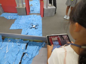 タブレットでトイドローンを操作する児童