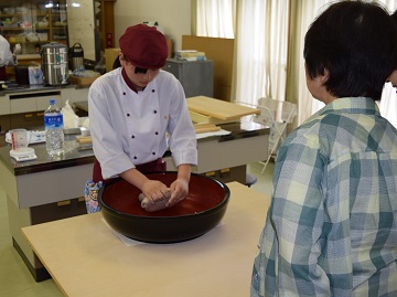 高校生が手打ちそばをこねる様子を見学するお客様