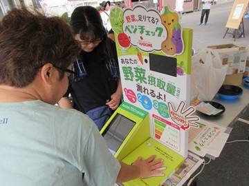 ベジチェックで野菜摂取量を計測する来場者