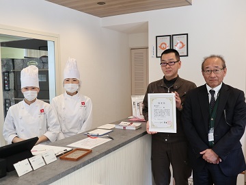 認定証を手にする藤野取締役事業部長と関係者との集合写真