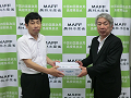 大木事務局長へ引き渡す守屋地方参事官