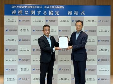 協定書を掲げる郷局長（右）と入江頭取（左）