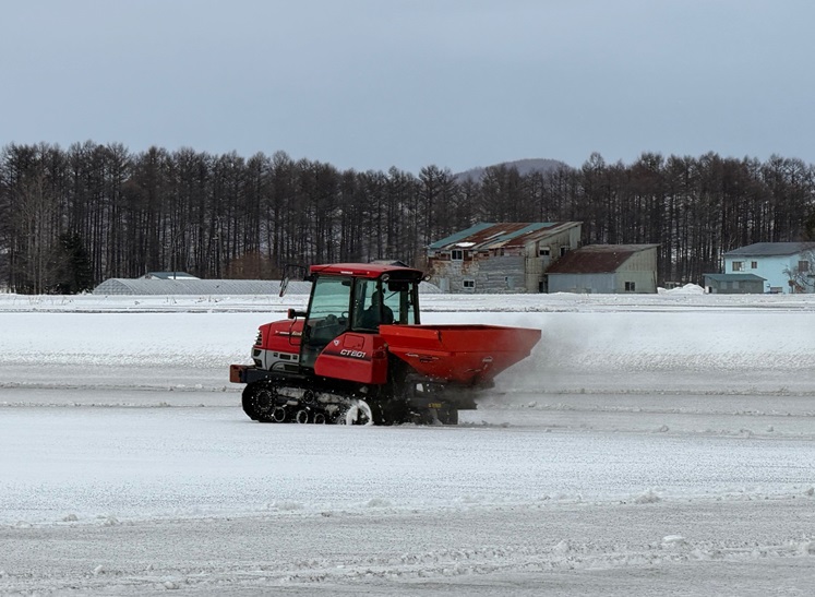 トラクターで融雪剤を撒いている