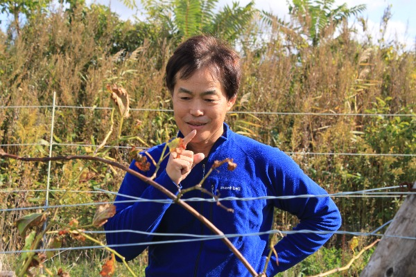 平成27年に就農した鶴山さんが醸造用ぶどうを前に話している様子の写真