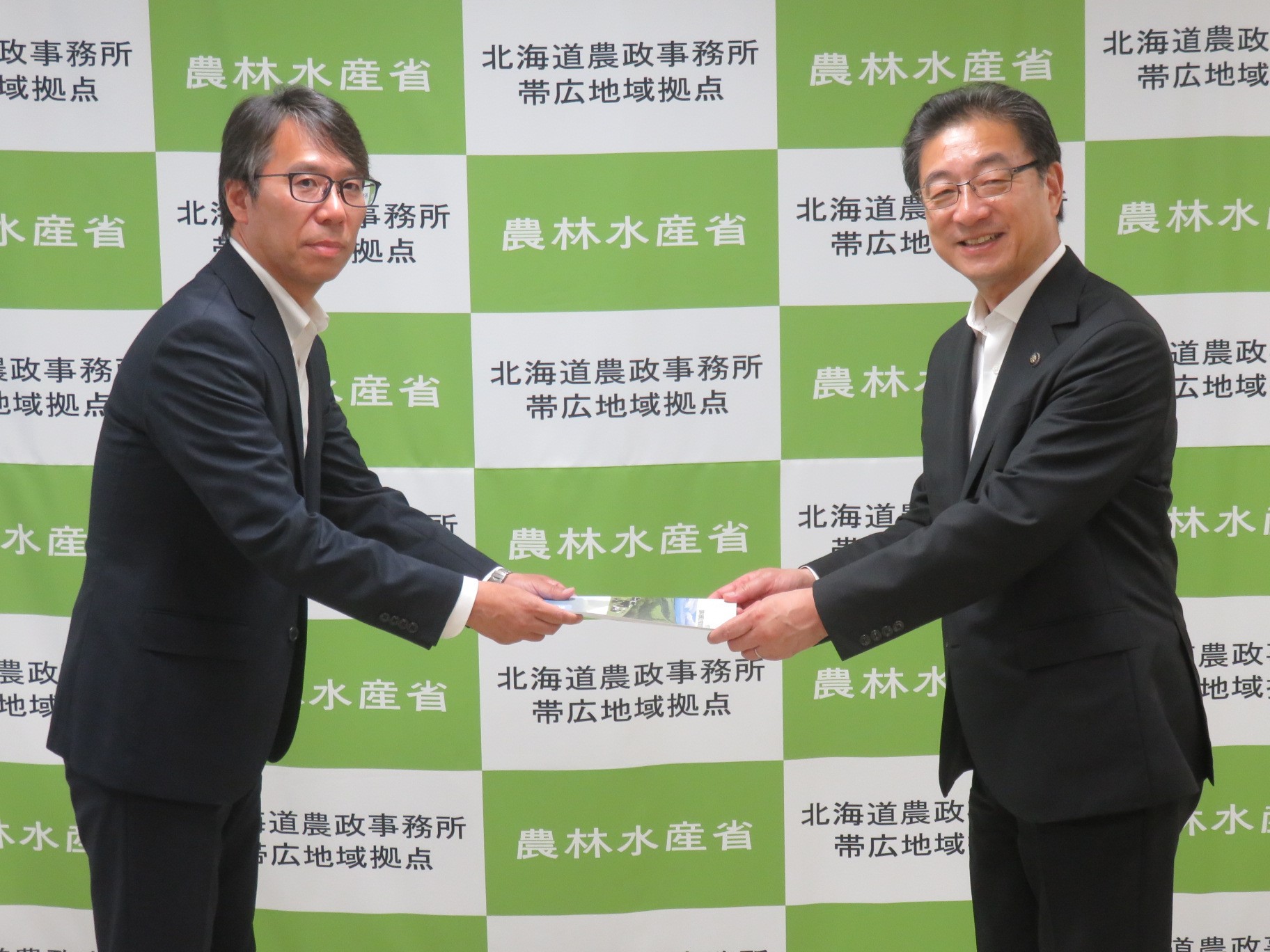 米沢会長（右）から田中地方中参事官への要望書提出