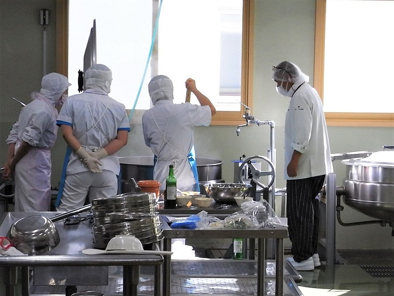 調理場での中野秀明シェフと職員の共同作業