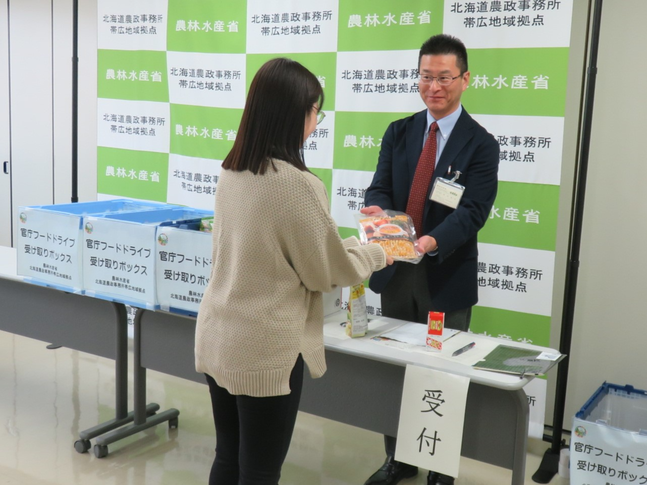 食品を提供する職員（左）