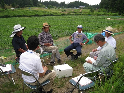 すいか畑を背景に意見交換