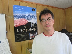 自社ブランド肉のポスターと森川さん