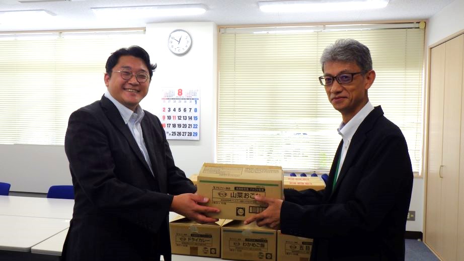 フードバンクに備蓄食品を手渡す田中所長