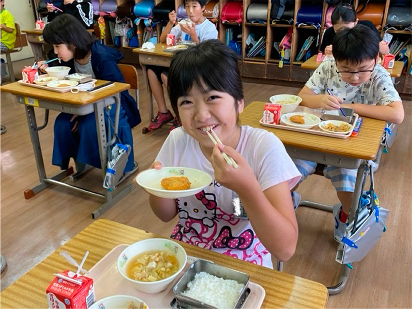 給食でメカジキメンチコロッケを食べる児童