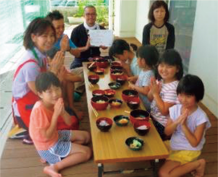 地域住民からいただいた野菜を使い、みんなで作った料理をみんなで食べる風景。