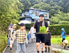 苗をもって田んぼに向かう選手と子供