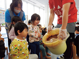 調理室前で食材の説明を受ける子供たち