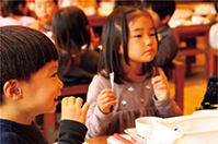 イワシの丸干しを食べる園児