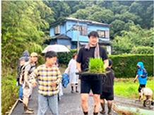 イネの苗をもつ選手と子供