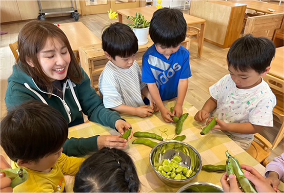 子供と大人がソラマメの皮をむく様子