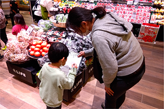 店舗で野菜を探すゲームに参加する親子