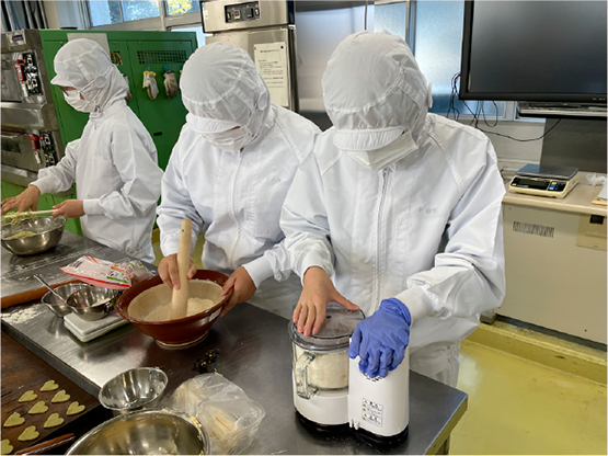 白衣を着た高校生徒がクッキーを作っている。