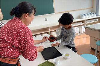 お茶のいれ方を子供が教わっている様子