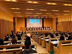 ホールで意見交換する人々とそれを聴く学生たち