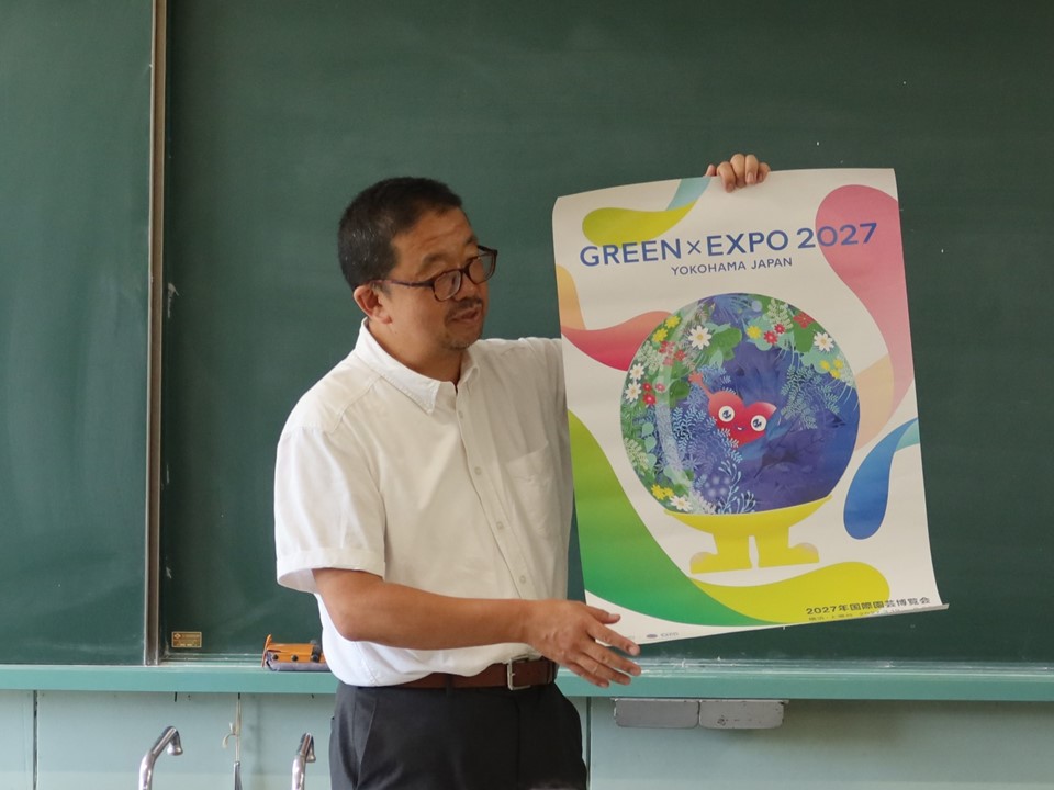 2027年国際園芸博覧会について職員がポスターで紹介している様子