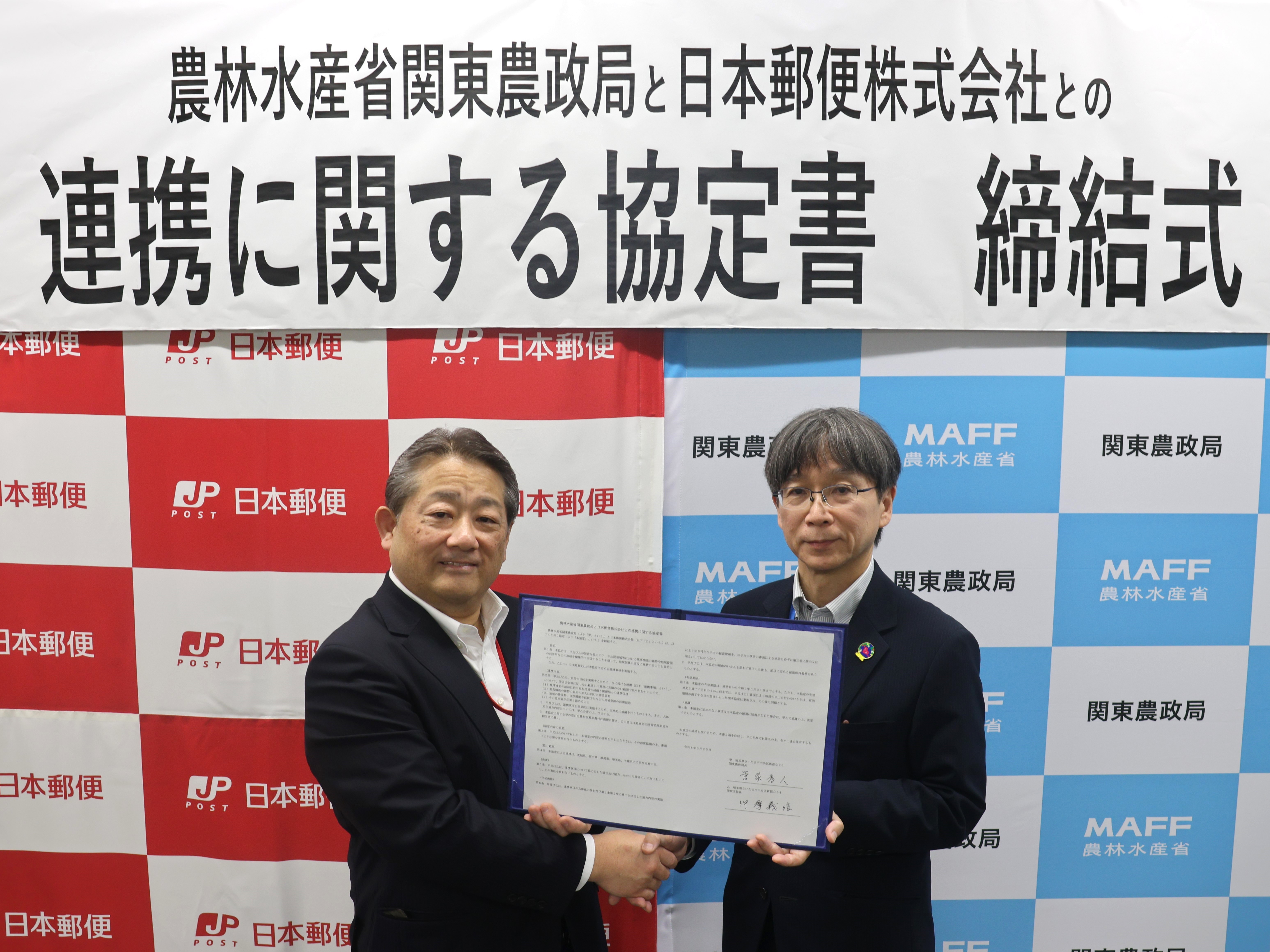 協定書を手に記念撮影を行う、日本郵便株式会社 仲摩常務執行役員（関東支社長）（左）と関東農政局 菅家局長（右）