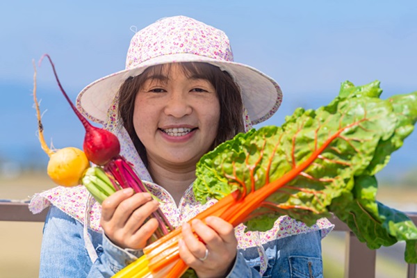 女性生産者が野菜と写る様子