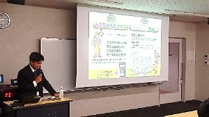 みえるらべるクイズの説明をする若手職員