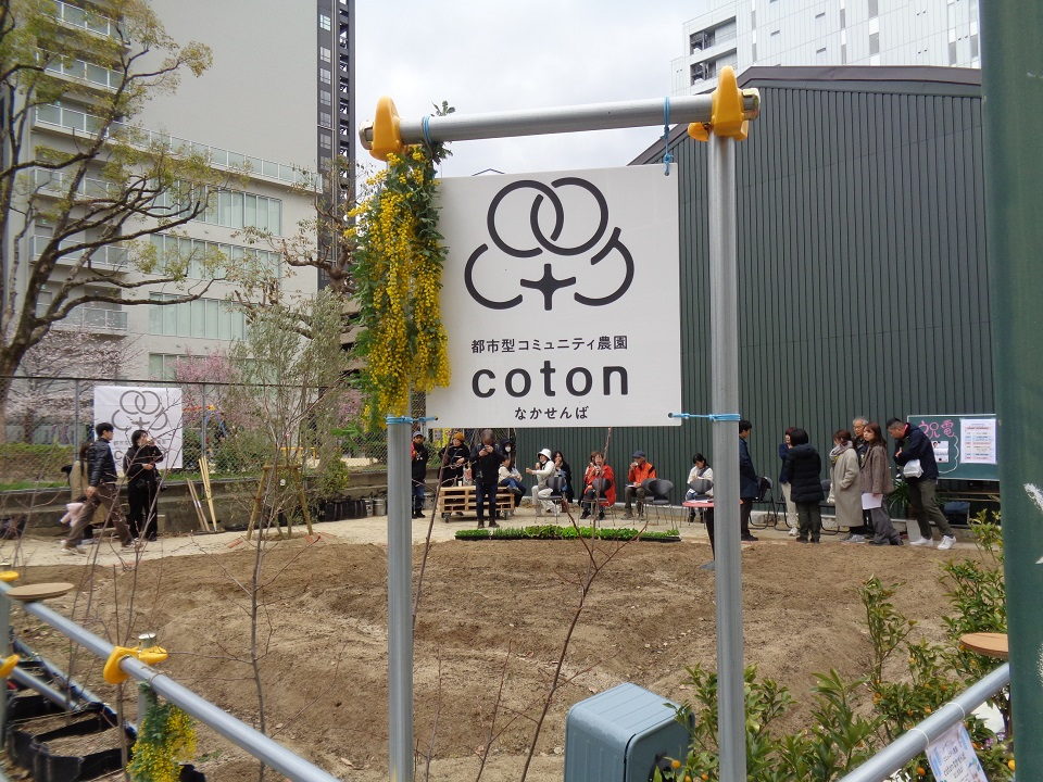 cotonなかせんばの看板とその奥に広がる農園