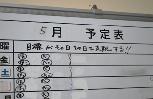 「目標がその日その日を支配する」と書かれたホワイトボード