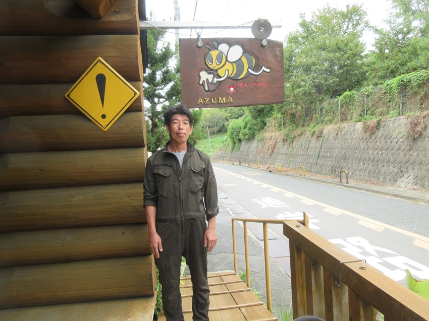 アズマ養蜂場看板前に立つあずまさん