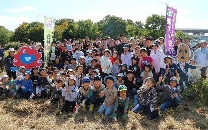 宣伝旗を手に持ち子供達や大人の集合写真