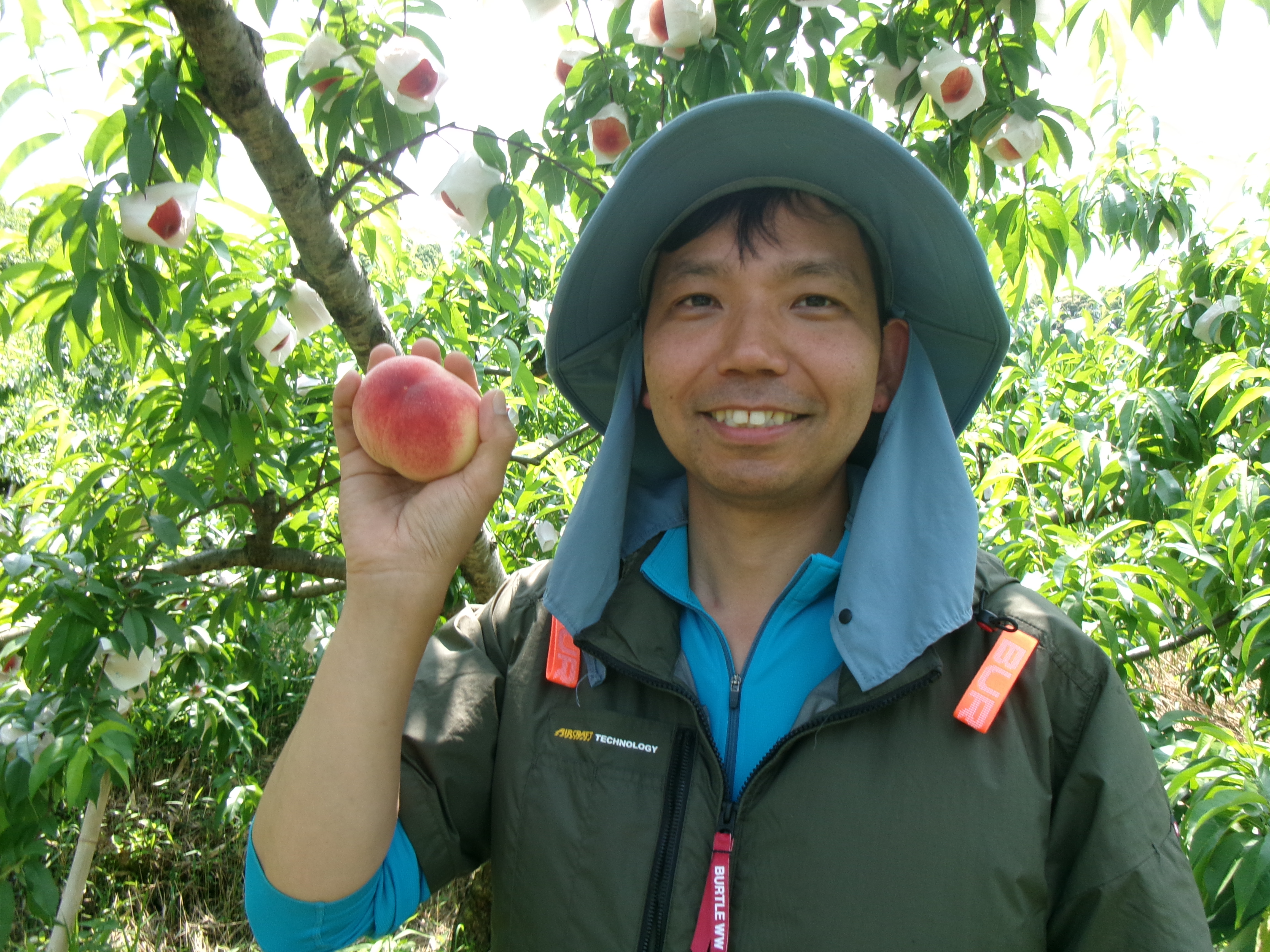桃を片手に笑顔の山本康平さん