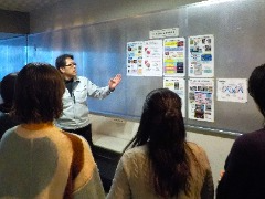 施設見学中にポスターで学生へ説明する様子