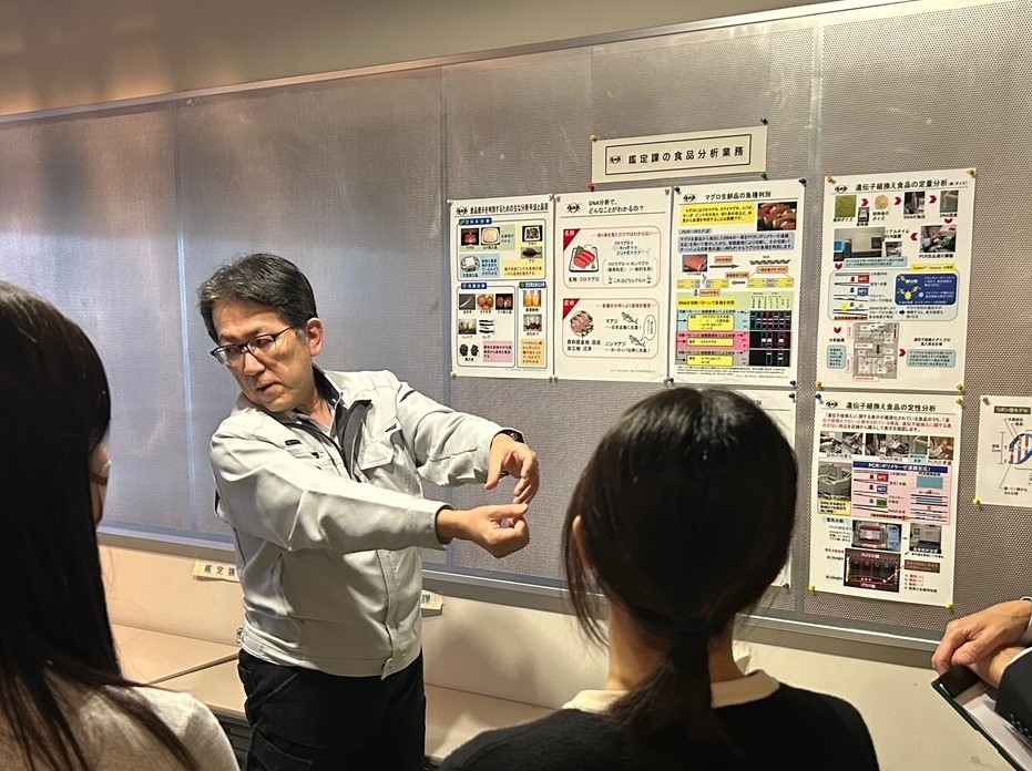施設見学中にポスターで学生に説明する様子