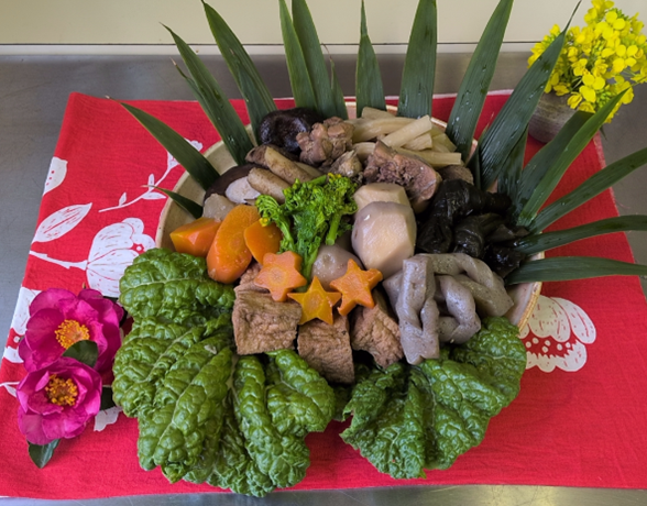 MAFFの仲間たちが作成した煮しめは、有機の野菜、こんにゃく、みりんなど、環境にやさしい食材を使い、盛り付けにもこだわって、「みえるらべる」をイメージした星型のにんじん（有機）を飾りつつ、春らしく仕上げました。