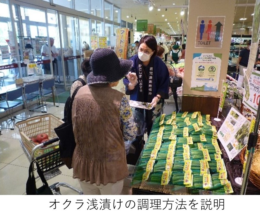 マスク着用のスタッフが高齢女性客にオクラ浅漬けの調理方法を説明の様子