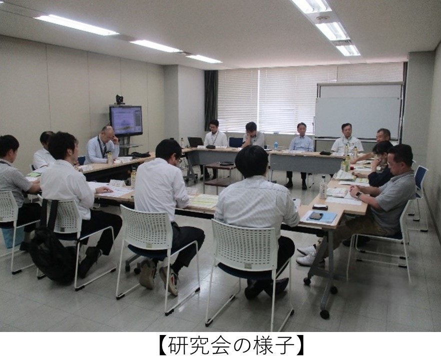 会議室で約12～13名の参加者が机をコの字型に配置して会議を行っている写真