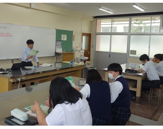 資料を手に説明する職員と資料を見る生徒達