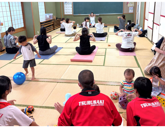 和室で、大人はヨガをし、子どもたちはおもちゃで遊んでいます。