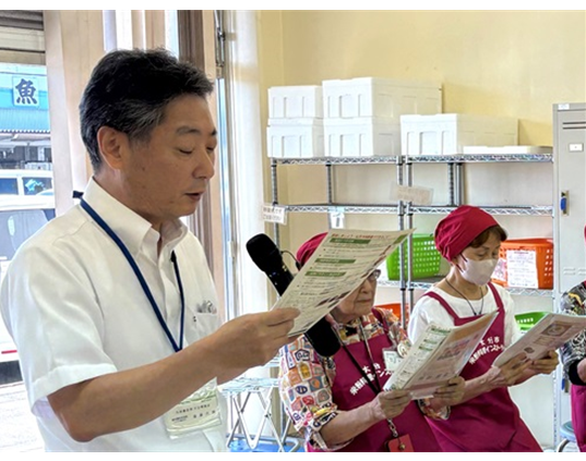 親子料理教室で配付したチラシの内容について説明する県拠点職員