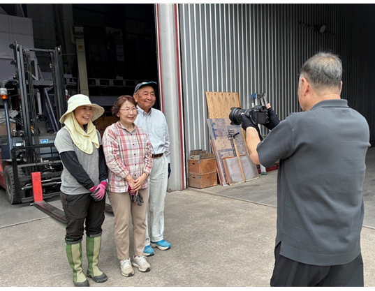 倉庫の前で並んだ参加者を、写真家が撮影しています。
