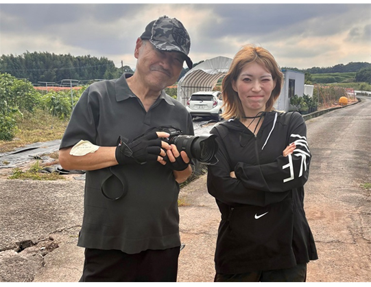 写真家と農業女子が並び、撮影の合間にカメラを確認しています。