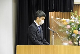 壇上で祝辞を述べる山口参事官