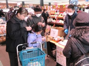 マイヤ店舗内の有機農産物販売コーナーで試食する親子連れ