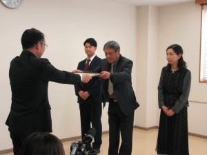 島尾地方参事官から山本代表取締役への賞状授与の様子