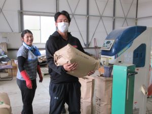 30kgの米袋を笑顔で抱える学生